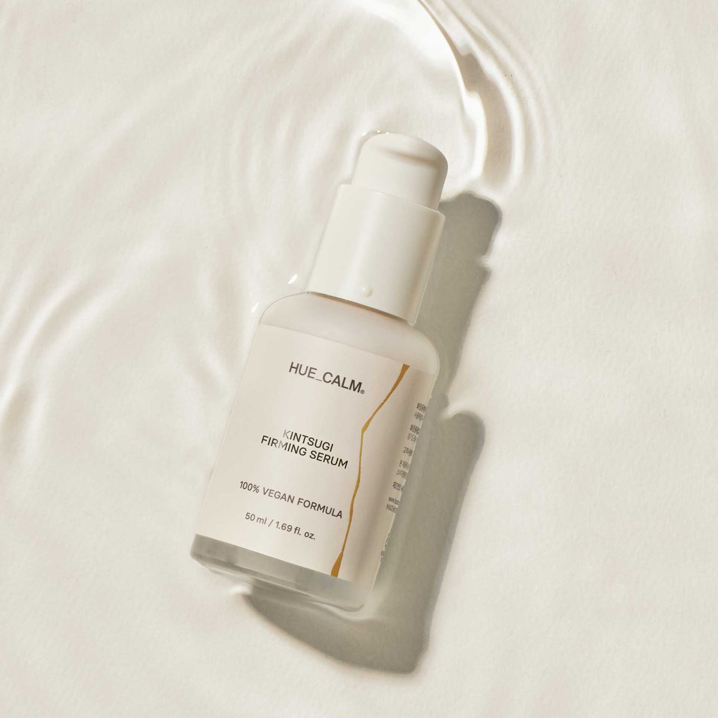 Flat lay image of Huecalm Firming Serum on white surface with glow