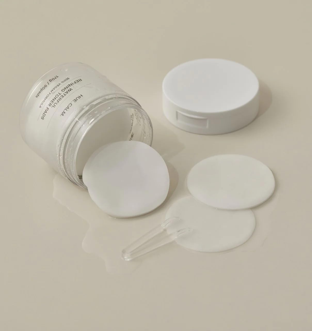 Huecalm - Opened jar of toner pads with visible contents and included clear tweezers for hygienic use.