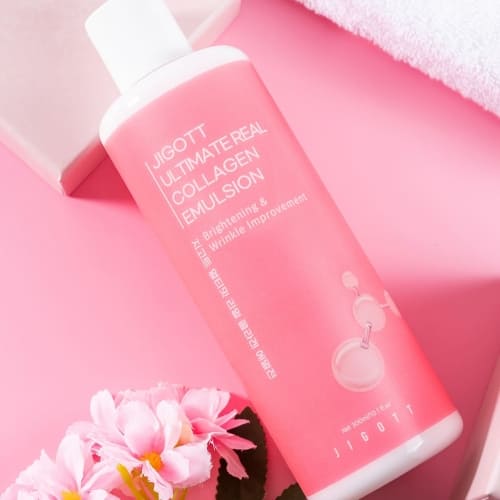 Flatlay of collagen emulsion with pink background, towel, and flowers