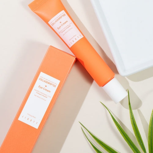 Angled top-down shot of Jigott Eye Cream and packaging on a cream-colored background