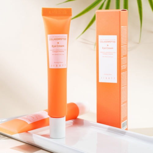Jigott Eye Cream standing upright next to its packaging on a tray with soft background lighting