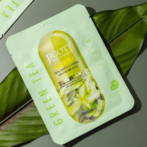 Green tea mask styled on tropical leaf background with angled lighting