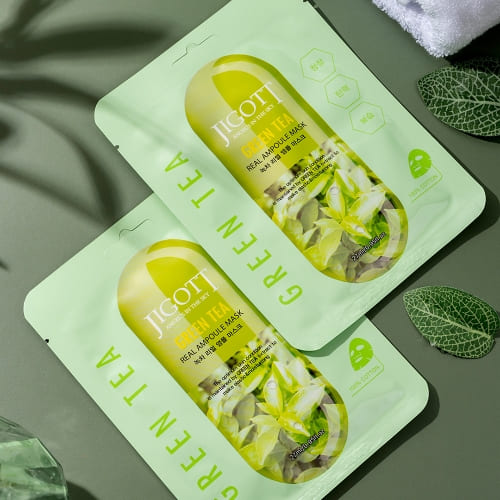 Two green tea ampoule masks styled with green decor and leaves for spa display