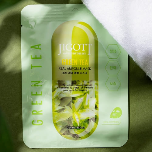 Single green tea ampoule mask with soft towel and natural shadow styling