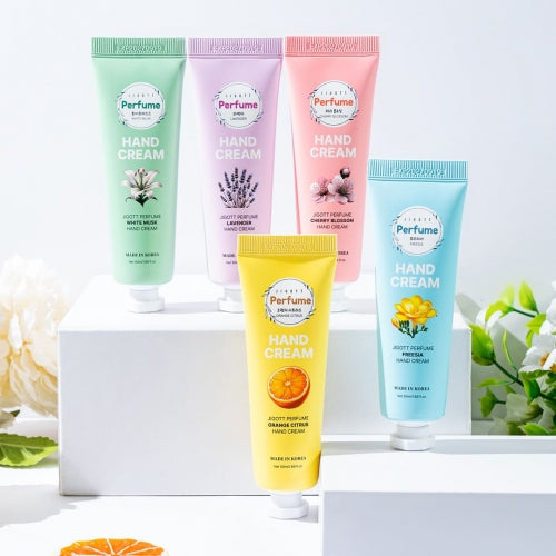Five colorful hand cream tubes arranged on white pedestal with natural floral decor