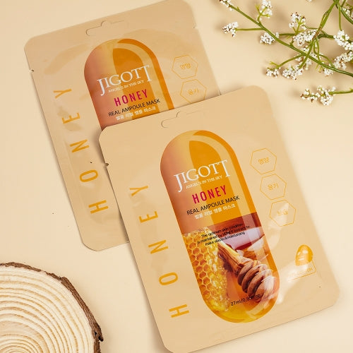Two honey sheet masks displayed with natural wood and floral props