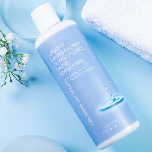 Flatlay of emulsion bottle on blue background with towel and moisture bubbles
