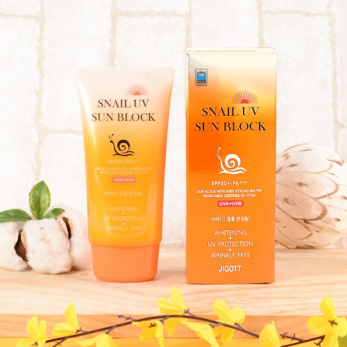 Jigott Snail UV Sunscreen with matching outer box and flowers on wood surface