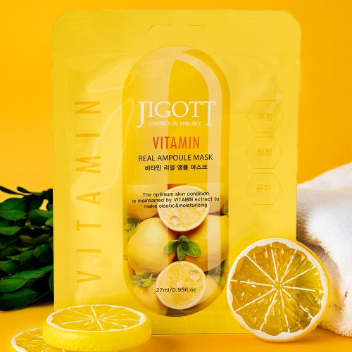 Single vitamin sheet mask displayed upright with fresh lemon slices and yellow background