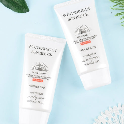 Two Jigott Whitening UV Sunscreen tubes on soft blue flatlay with foliage