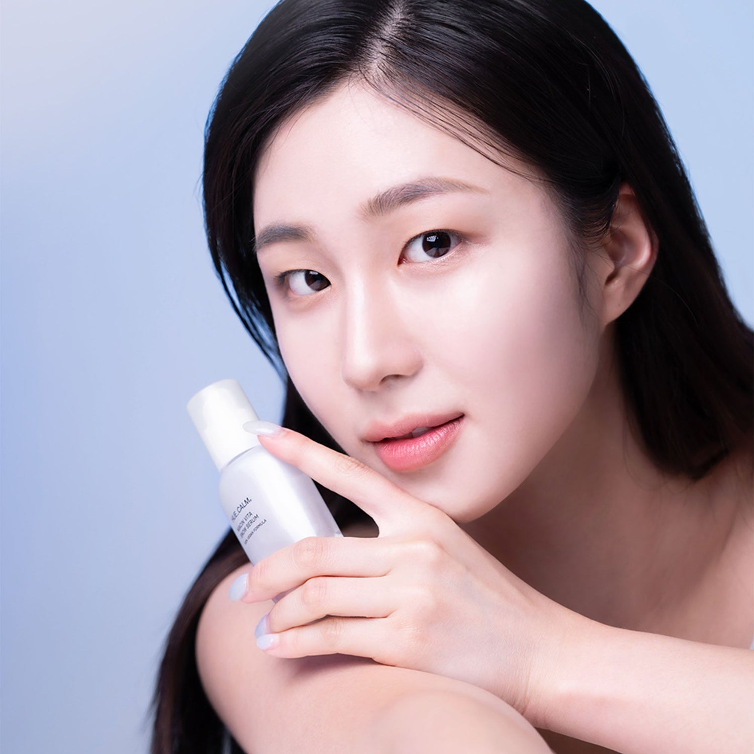 Korean woman holding brightening serum bottle with clear, glowing skin – K-beauty wholesale product image for brightening skincare collection