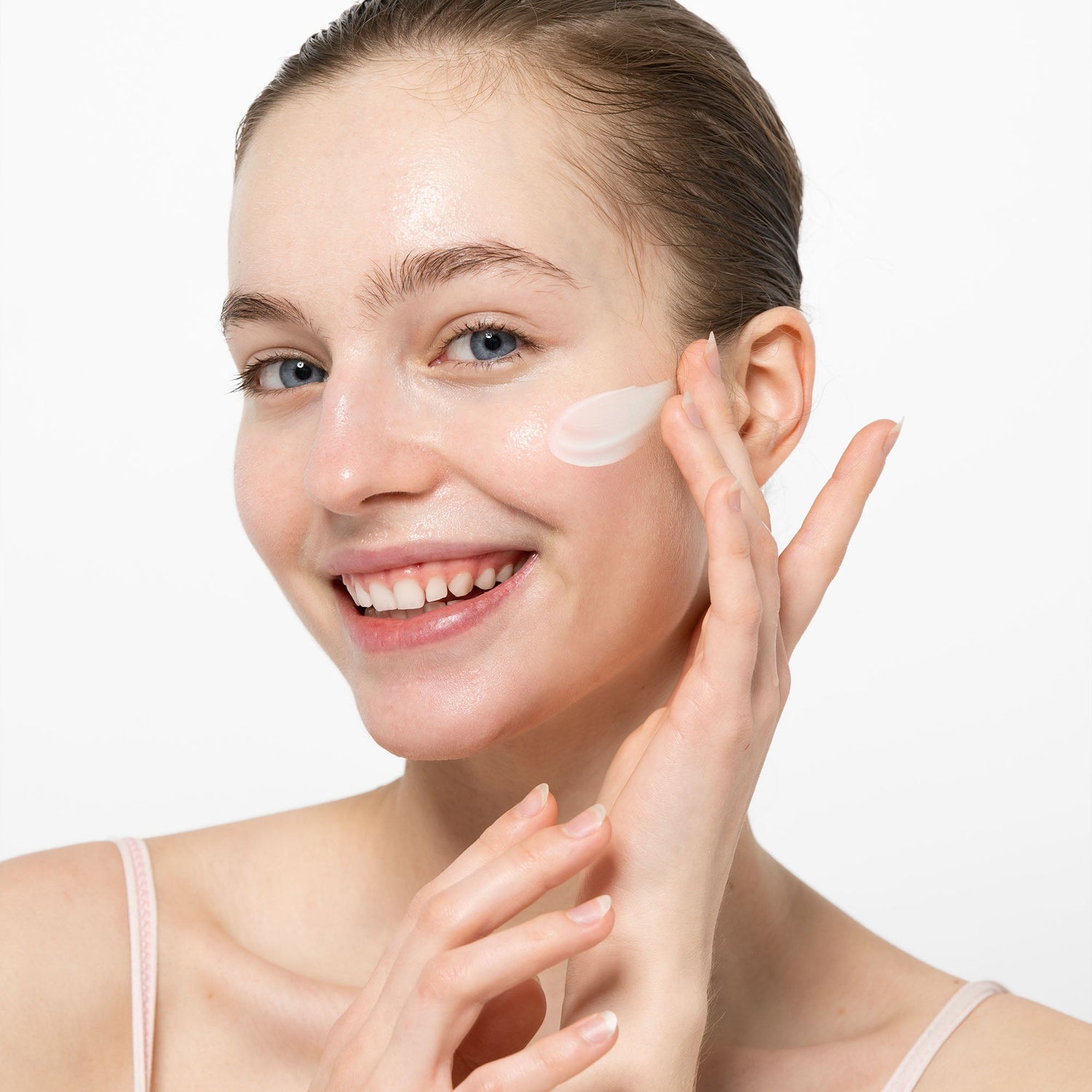 Smiling woman applying anti-aging cream on her face – Korean skincare product image for wrinkle care and skin elasticity in K-beauty wholesale collection