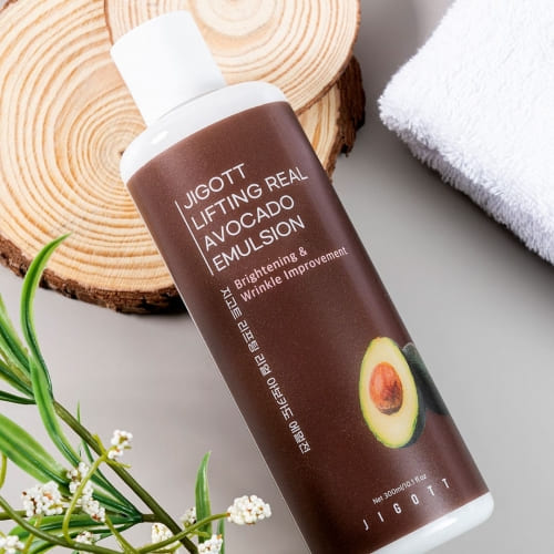 Avocado emulsion bottle laid on towel and wood with botanical decor for natural skincare theme