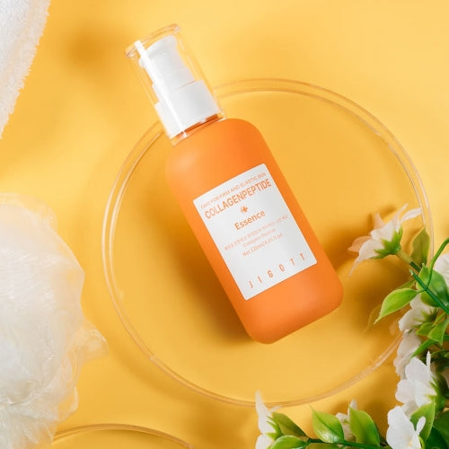 Flat-lay of Jigott Collagen Peptide Essence bottle on yellow background with floral accents