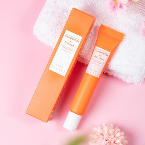 Jigott Collagen Eye Cream with packaging surrounded by towel and soft pink floral decor
