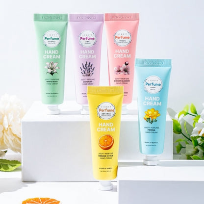 Five colorful hand cream tubes arranged on white pedestal with natural floral decor